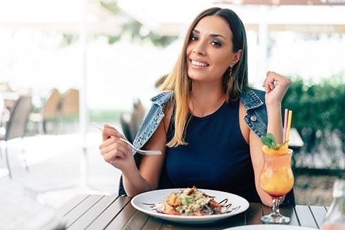 Middle aged woman eating a healthier meal at an outdoor restaurant.